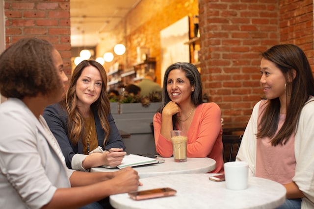 Four people talking around tables in a cafe